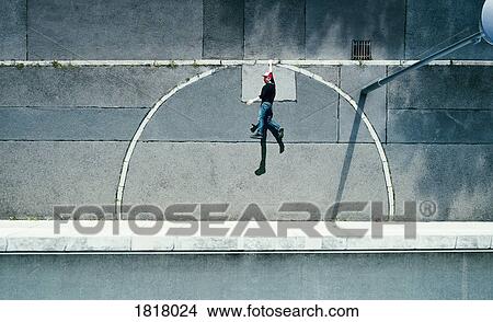 Picture - View from above young man hanging from urban curb. Fotosearch