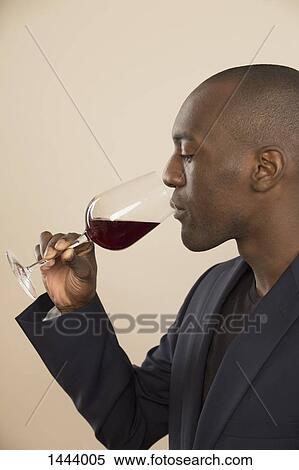 Well-dressed man tasting red wine against colored background View Large Photo Image Stock Photography - Well-dressed man tasting red wine against colored background. Fotosearch