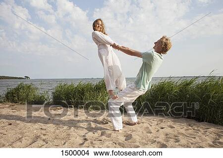 Woman balancing on friend's knee at beach against sky View Large Photo Image Picture - Woman balancing on friend's knee at beach against sky. Fotosearch