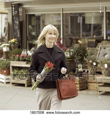 Stock Photo - Woman carrying bunch of tulips on urban sidewalk. Fotosearch