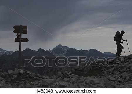 Woman hiking on rocks at mountain against cloudy sky View Large Photo Image Stock Photo - Woman hiking on rocks at mountain against cloudy sky. Fotosearch