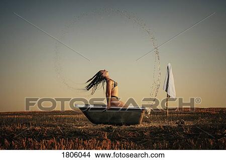 Woman in bikini splashing hair in bathtub in rural field View Large Photo Image Picture - Woman in bikini splashing hair in bathtub in rural field. Fotosearch