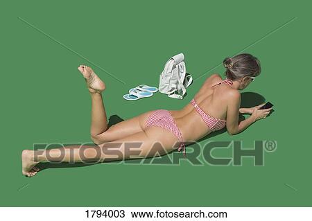Woman in bikini sunbathing on green background View Large Photo Image Stock Image - Woman in bikini sunbathing on green background. Fotosearch