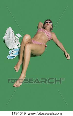 Woman in bikini sunbathing on green background View Large Photo Image Stock Photo - Woman in bikini sunbathing on green background. Fotosearch