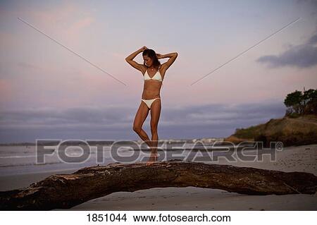 Woman in bikini walking on driftwood on beach at dusk View Large Photo Image Picture - Woman in bikini walking on driftwood on beach at dusk. Fotosearch