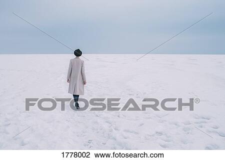 Woman in coat and hat walking in snow covered landscape View Large Photo Image Stock Image - Woman in coat and hat walking in snow covered landscape. Fotosearch