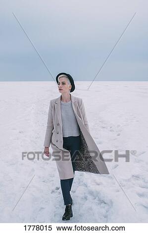 Woman in coat and hat walking in snow covered landscape View Large Photo Image Stock Photography - Woman in coat and hat walking in snow covered landscape. Fotosearch