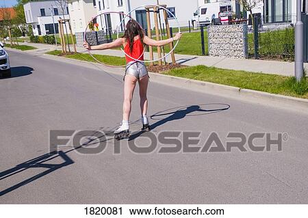 Woman in short shorts with plastic hoops roller skating on sunny neighborhood road View Large Photo Image Stock Image - Woman in short shorts with plastic hoops roller skating on sunny neighborhood road. Fotosearch