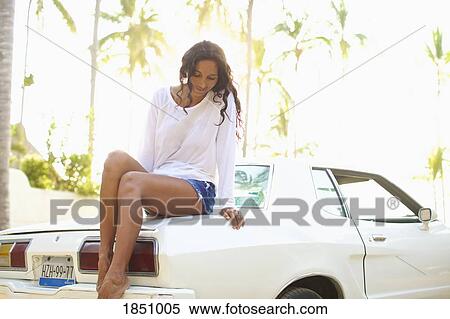Woman in shorts sitting on car View Large Photo Image Stock Photography - Woman in shorts sitting on car. Fotosearch