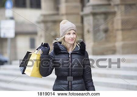 Picture - Woman in warm clothing carrying shopping bags. Fotosearch