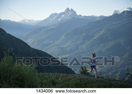 Woman jogging on path in mountain range View Large Photo Image Stock Photograph - Woman jogging on path in mountain range. Fotosearch