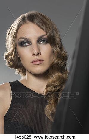 Woman looking away while standing by curtain View Large Photo Image Stock Photo - Woman looking away while standing by curtain. Fotosearch