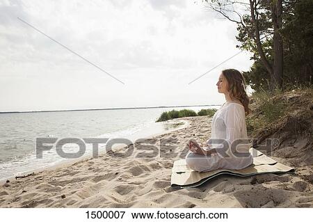 Woman meditating on sea shore at beach against sky View Large Photo Image Stock Photo - Woman meditating on sea shore at beach against sky. Fotosearch