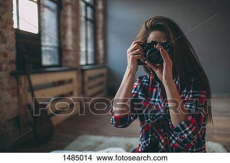 Woman photographing through SLR camera in bedroom at home View Large Photo Image Picture - Woman photographing through SLR camera in bedroom at home. Fotosearch