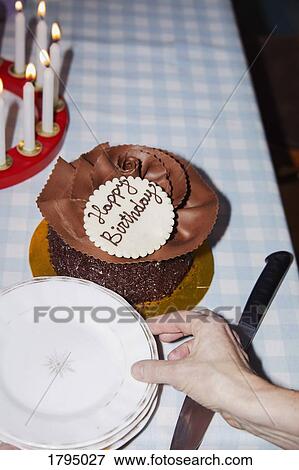 Stock Photo - Woman reaching for plate next to chocolate birthday cake. Fotosearch