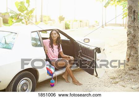 Stock Photograph - Woman sitting in car on sunny beach. Fotosearch