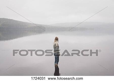 Woman standing in lake against sky during foggy weather, Jaervsoe, Haelsingland, Sweden View Large Photo Image Stock Image - Woman standing in lake against sky during foggy weather, Jaervsoe, Haelsingland, Sweden. Fotosearch