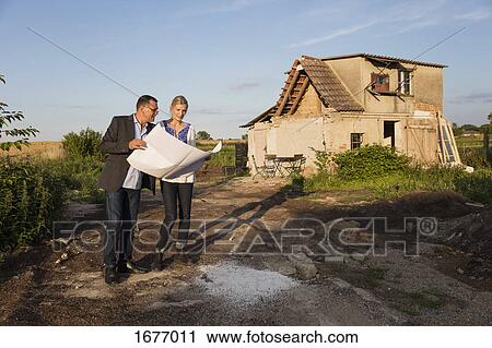 Woman standing with estate agent while reading documents against house on sunny day View Large Photo Image Stock Image - Woman standing with estate agent while reading documents against house on sunny day. Fotosearch