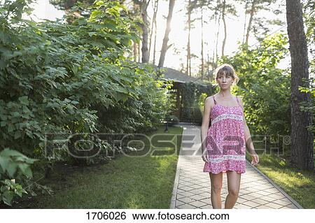 Woman wearing pink dress walking on pathway amidst plants in yard View Large Photo Image Stock Photograph - Woman wearing pink dress walking on pathway amidst plants in yard. Fotosearch