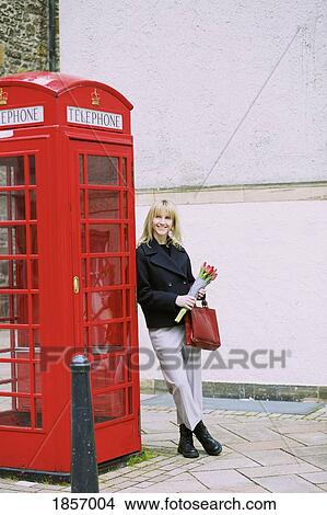 Woman with bunch of tulips leaning against red telephone box View Large Photo Image Picture - Woman with bunch of tulips leaning against red telephone box. Fotosearch