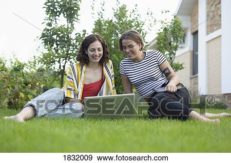 Women friends using laptop in grass View Large Photo Image Stock Photo - Women friends using laptop in grass. Fotosearch