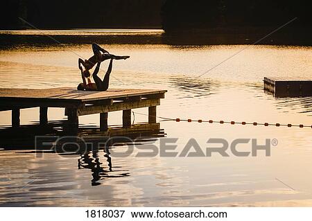 Women practicing acro yoga on lakeside dock at dusk View Large Photo Image Stock Photo - Women practicing acro yoga on lakeside dock at dusk. Fotosearch