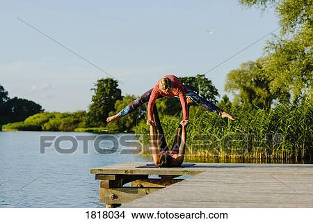 Women practicing acro yoga on sunny lakeside dock View Large Photo Image Picture - Women practicing acro yoga on sunny lakeside dock. Fotosearch