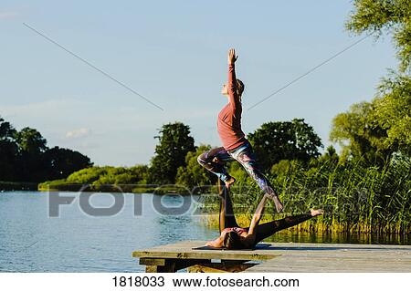 Women practicing acroyoga on sunny lakeside dock View Large Photo Image Stock Image - Women practicing acroyoga on sunny lakeside dock. Fotosearch