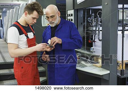 Workers standing with hand tool at printing press View Large Photo Image Stock Image - Workers standing with hand tool at printing press. Fotosearch