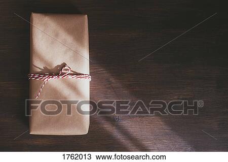 Wrapped Christmas present on wooden background with sunlight View Large Photo Image Stock Image - Wrapped Christmas present on wooden background with sunlight. Fotosearch