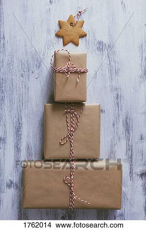 Picture - Wrapped Christmas presents arranged in the shape of a tree with a cookie star atop. Fotosearch