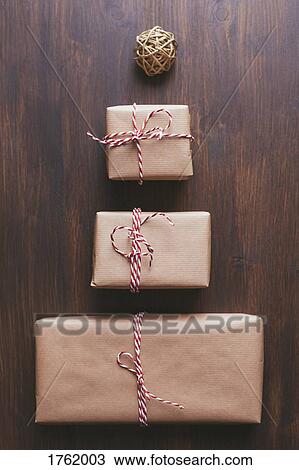 Stock Image - Wrapped Christmas presents arranged in the shape of a tree with a rubber band ball star atop. Fotosearch