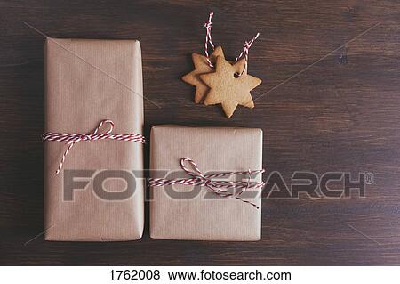 Stock Photo - Wrapped Christmas presents next to star shaped cookie decorations. Fotosearch