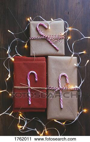 Wrapped Christmas presents with decorations and lights on wooden background View Large Photo Image Stock Image - Wrapped Christmas presents with decorations and lights on wooden background. Fotosearch