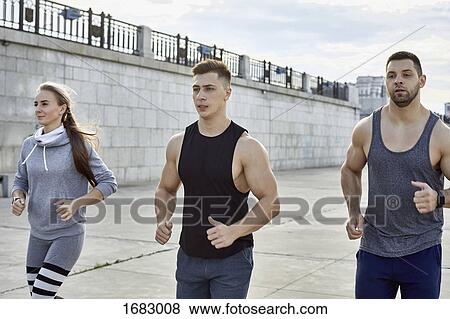 Young athletes jogging on footpath against wall View Large Photo Image Stock Photo - Young athletes jogging on footpath against wall. Fotosearch