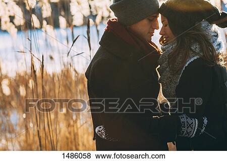 Young couple embracing while standing on field during winter View Large Photo Image Stock Photo - Young couple embracing while standing on field during winter. Fotosearch