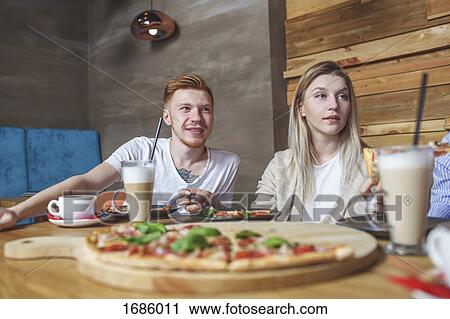 Young couple having pizza at restaurant View Large Photo Image Stock Image - Young couple having pizza at restaurant. Fotosearch