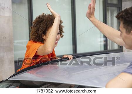 Young couple high-fiving over car View Large Photo Image Stock Image - Young couple high-fiving over car. Fotosearch