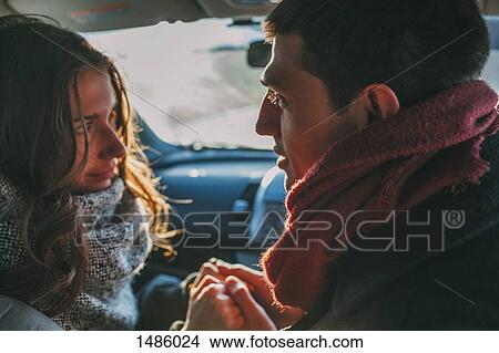 Picture - Young couple holding hands in car. Fotosearch