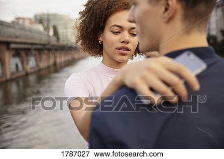 Stock Photo - Young couple hugging at riverside. Fotosearch