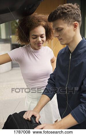 Young couple loading suitcase in car View Large Photo Image Stock Photo - Young couple loading suitcase in car. Fotosearch
