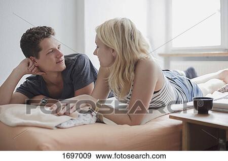 Stock Photo - Young couple lying on bed at home. Fotosearch