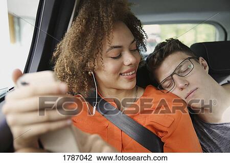 Young couple sleeping and listening to music in car View Large Photo Image Stock Image - Young couple sleeping and listening to music in car. Fotosearch