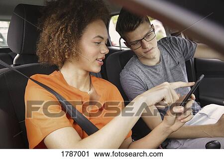 Young couple using smart phone GPS in car View Large Photo Image Stock Image - Young couple using smart phone GPS in car. Fotosearch