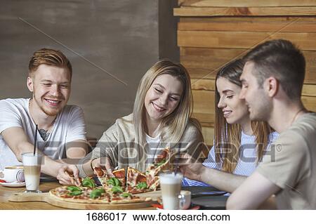 Young friends enjoying pizza at restaurant View Large Photo Image Stock Photo - Young friends enjoying pizza at restaurant. Fotosearch