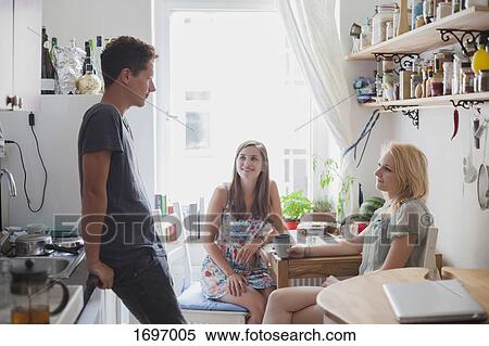 Stock Photography - Young friends in kitchen at home. Fotosearch