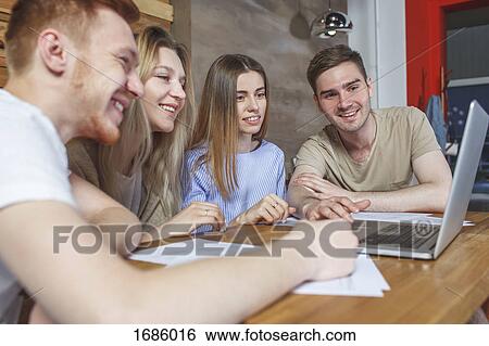 Young friends watching laptop while sitting at restaurant View Large Photo Image Stock Photograph - Young friends watching laptop while sitting at restaurant. Fotosearch