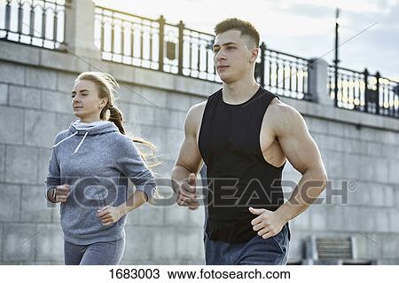 Young male and female athletes jogging against wall View Large Photo Image Stock Image - Young male and female athletes jogging against wall. Fotosearch