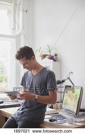 Young male university student using digital tablet at home View Large Photo Image Stock Image - Young male university student using digital tablet at home. Fotosearch