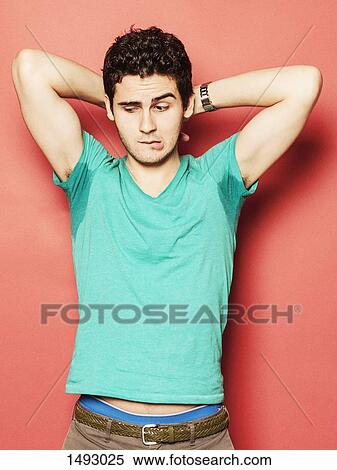 Young man biting lip while looking at sweaty armpit against red background View Large Photo Image Stock Photography - Young man biting lip while looking at sweaty armpit against red background. Fotosearch
